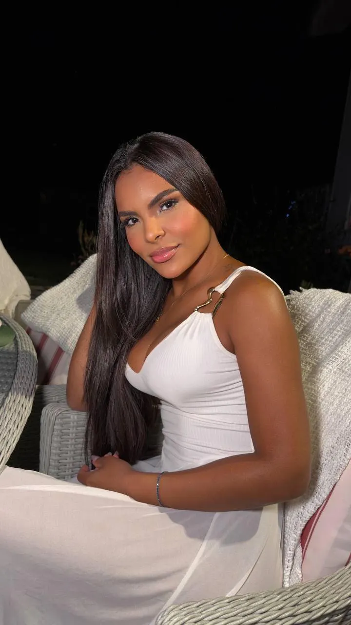Woman with long dark hair wearing a white dress.