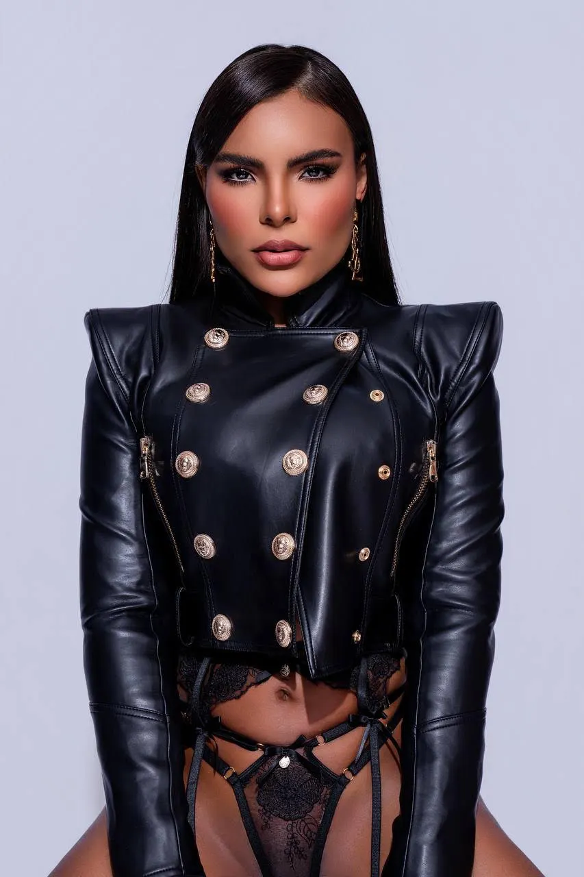 Woman in a cropped black leather jacket with gold buttons