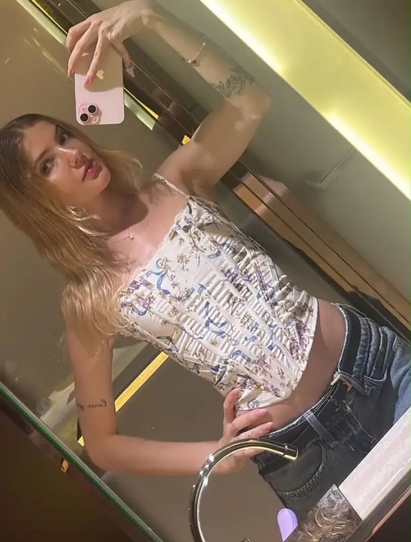 Woman taking a mirror selfie wearing a floral corset top.