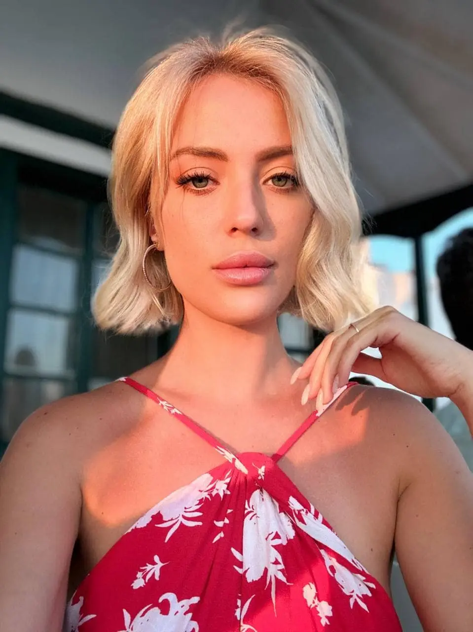 Blonde woman in red floral top during golden hour.