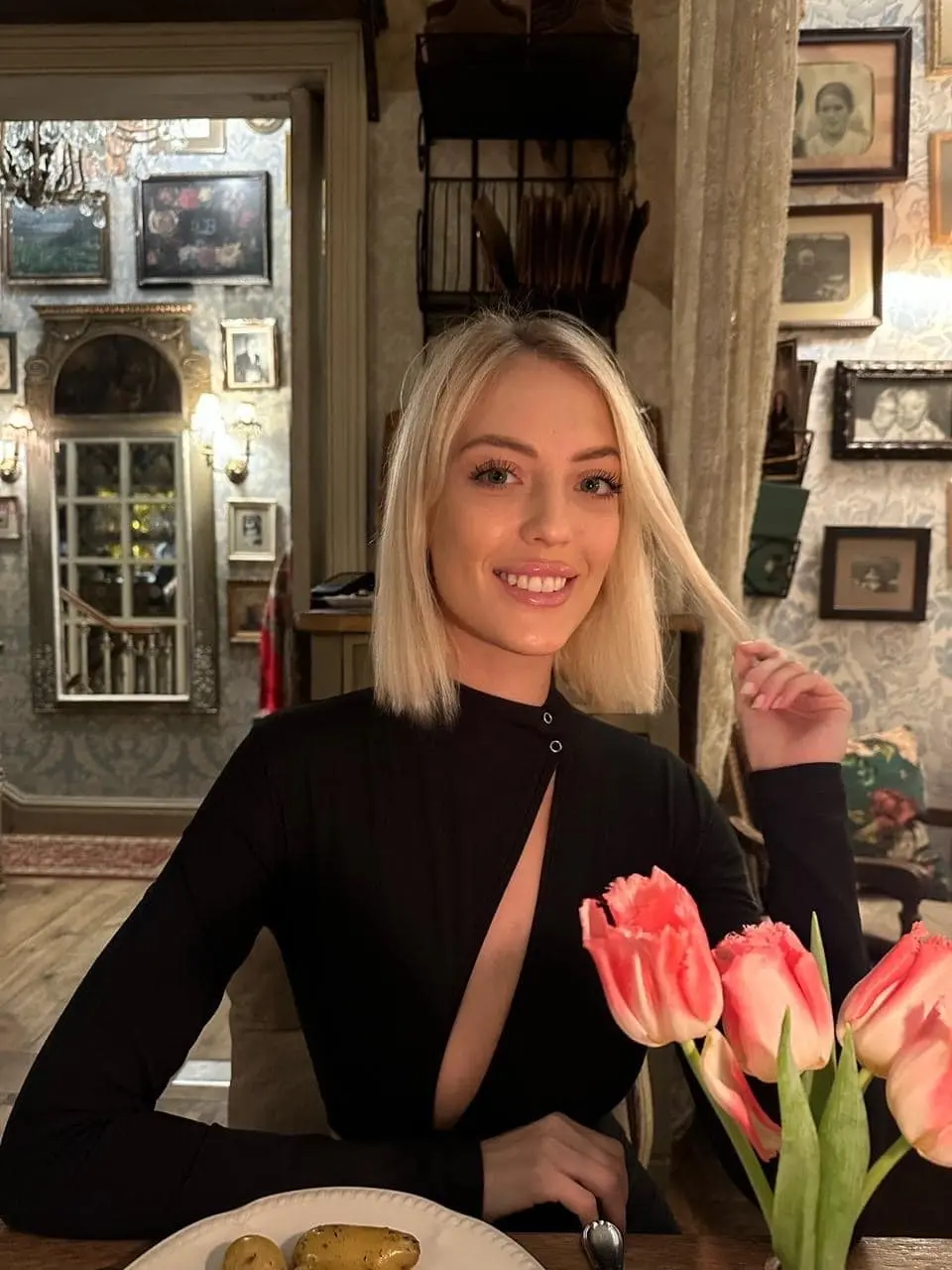 A blonde woman in a black top at a table.