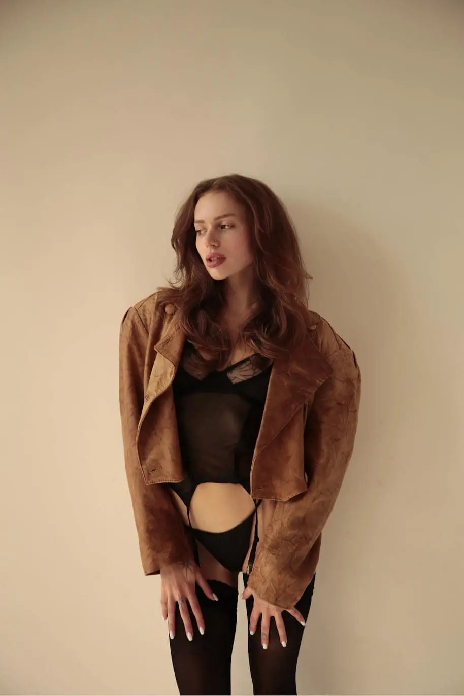 Woman in black lingerie and an oversized brown leather jacket.