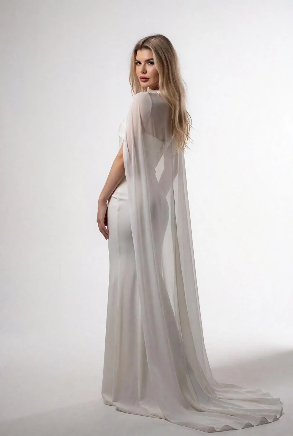 Woman in elegant white gown with long sheer cape