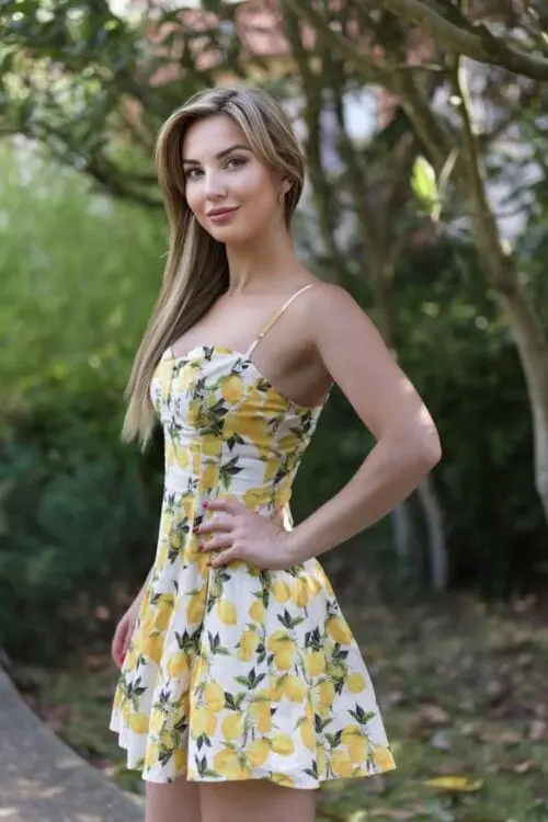 A woman wearing a lemon print sundress in a garden.