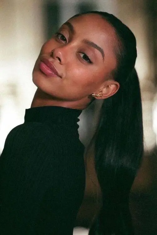 Close-up portrait of a woman with a sleek ponytail.