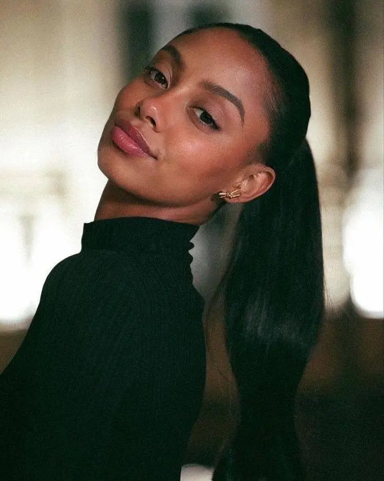 Close-up portrait of a woman with a sleek ponytail.