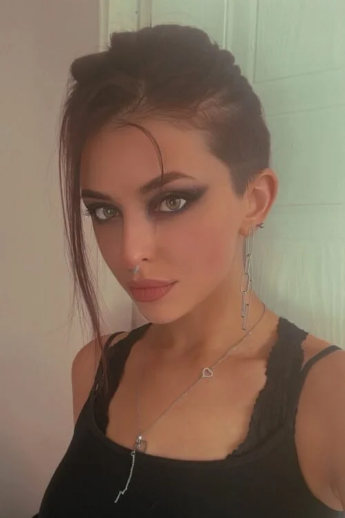 Portrait of woman with side-shaved hair and smoky eye makeup.