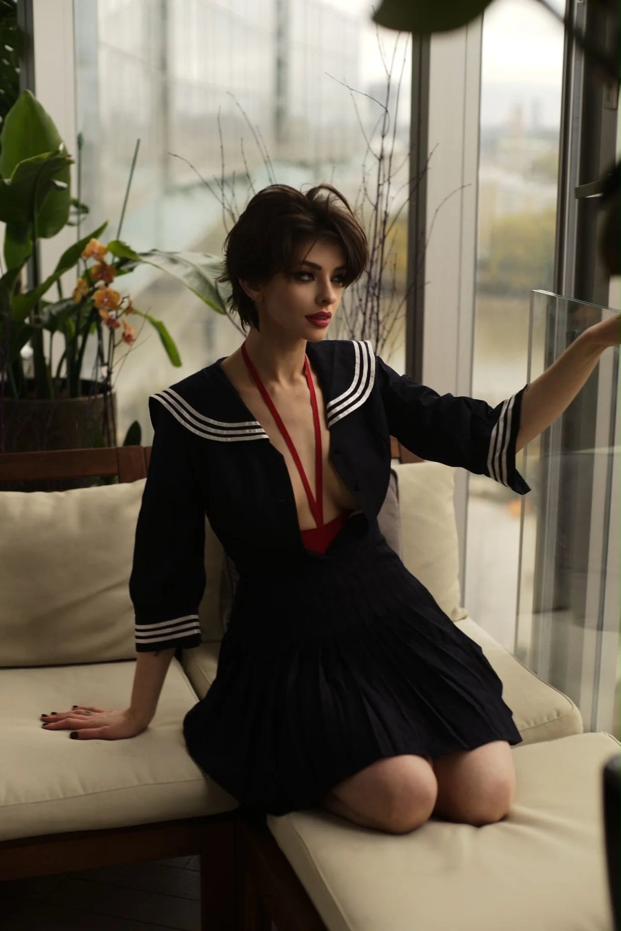 Woman in navy sailor-style dress kneeling on white cushions.