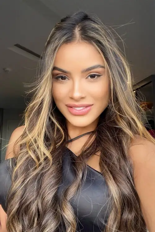Smiling woman with long wavy hair and blonde highlights.