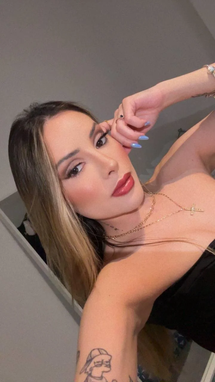 Woman with long hair and red lipstick wearing gold jewellery.