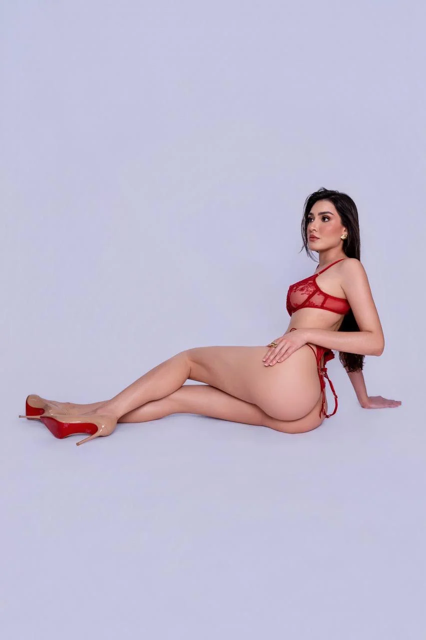 Woman posing in red lace lingerie and beige high heels.