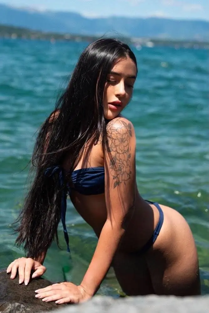 Woman in a blue bikini posing in clear water.