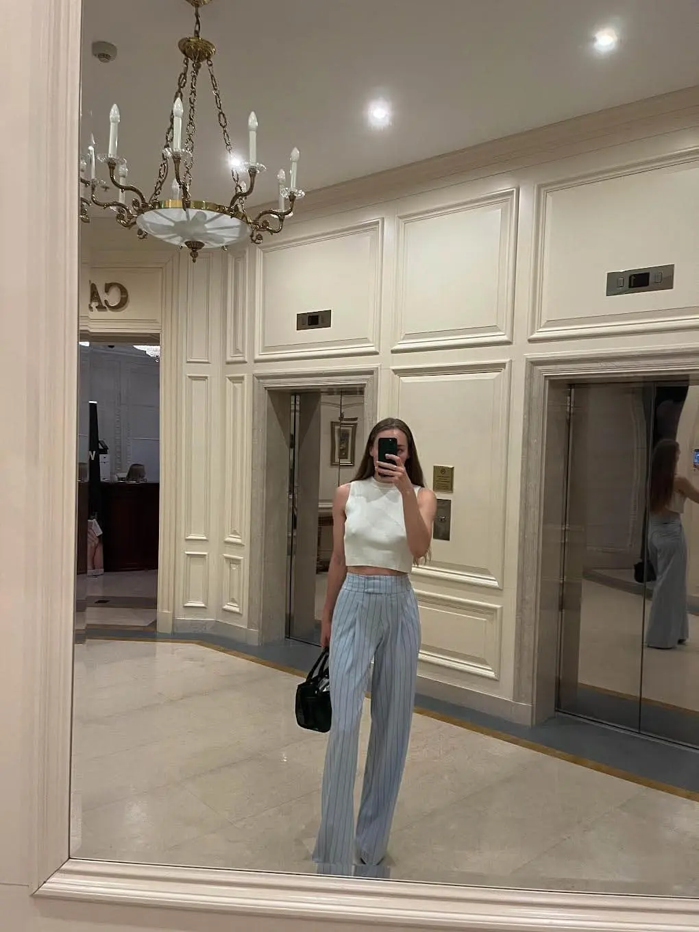 Woman taking mirror selfie in elegant lobby