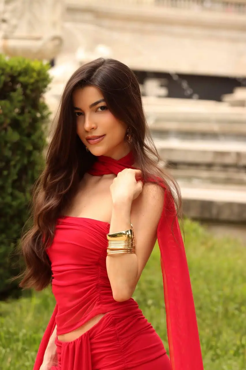 Woman in red dress with long brown hair posing.