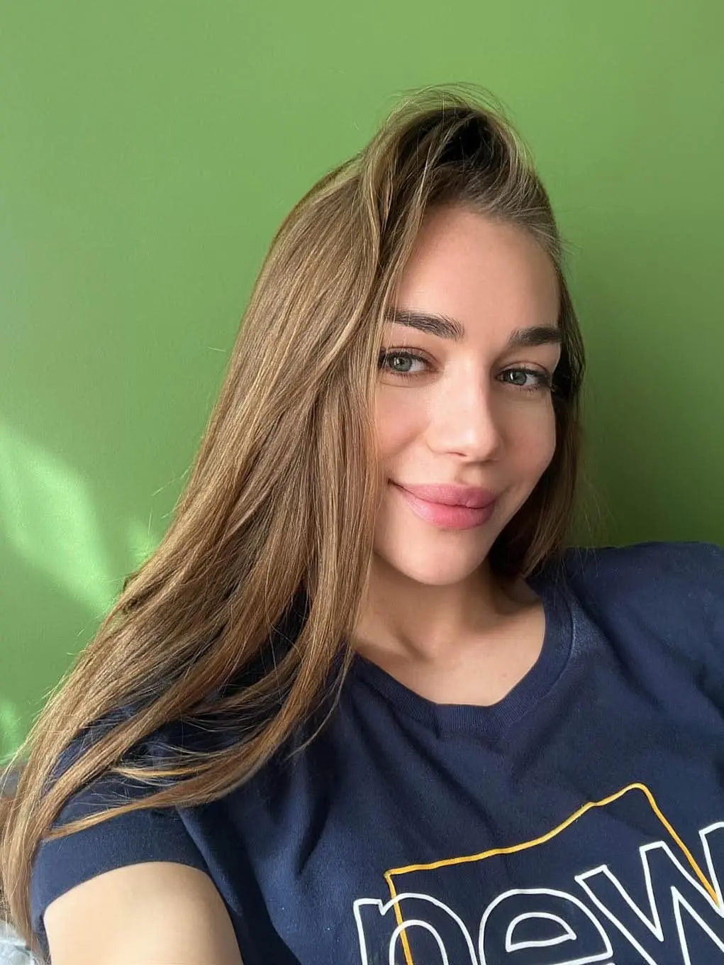 Woman taking selfie against green wall
