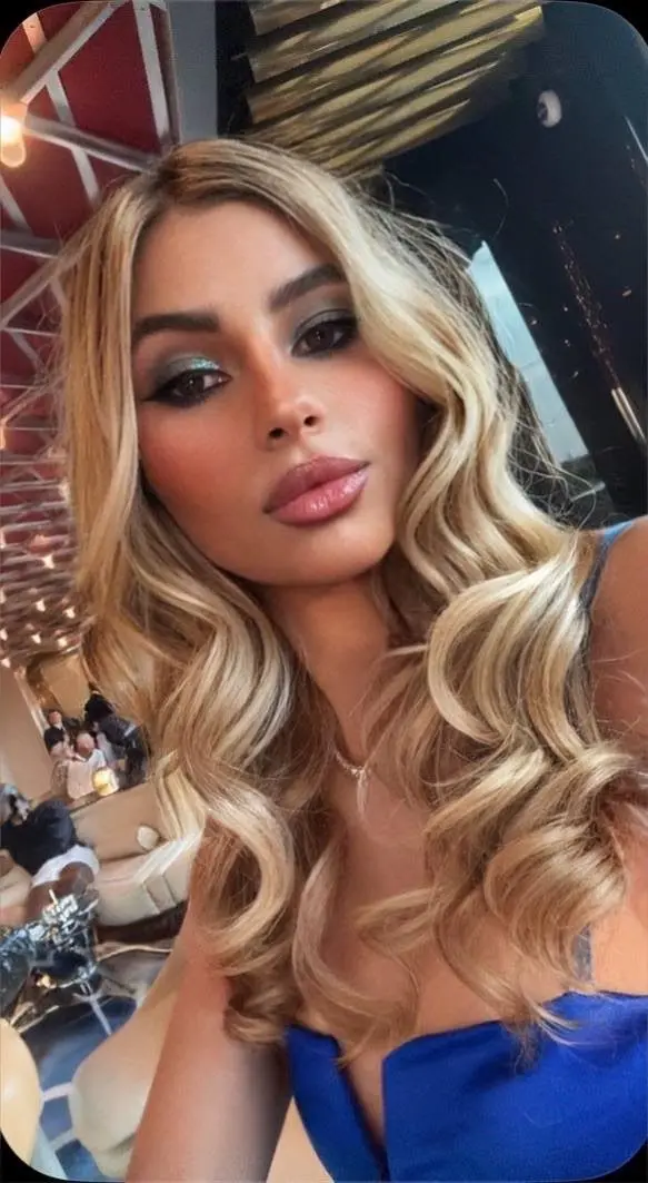 Blonde woman with wavy hair and glamorous makeup.