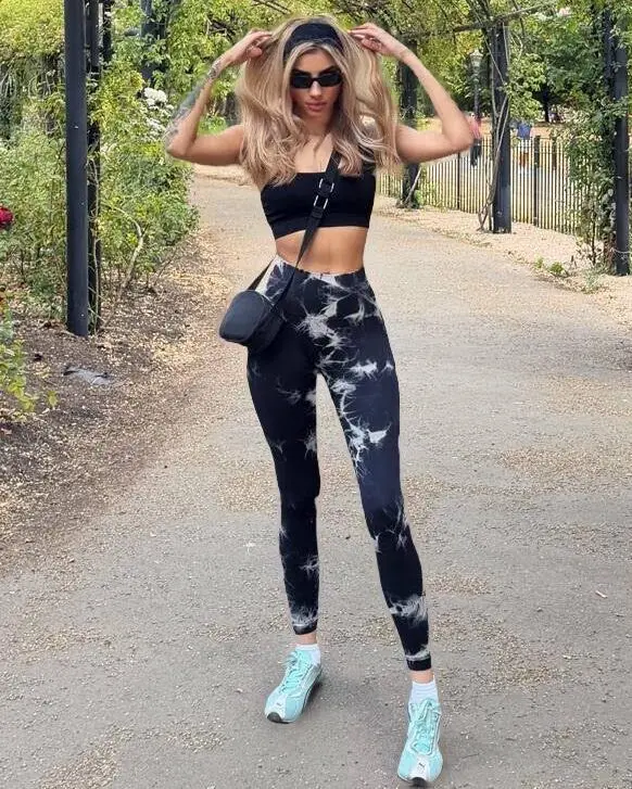 Woman in athletic wear posing under a garden archway.