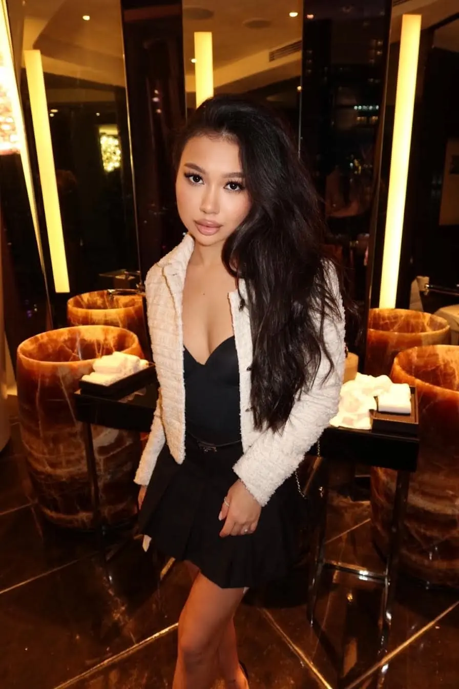 Woman posing in a white cardigan and black skirt.