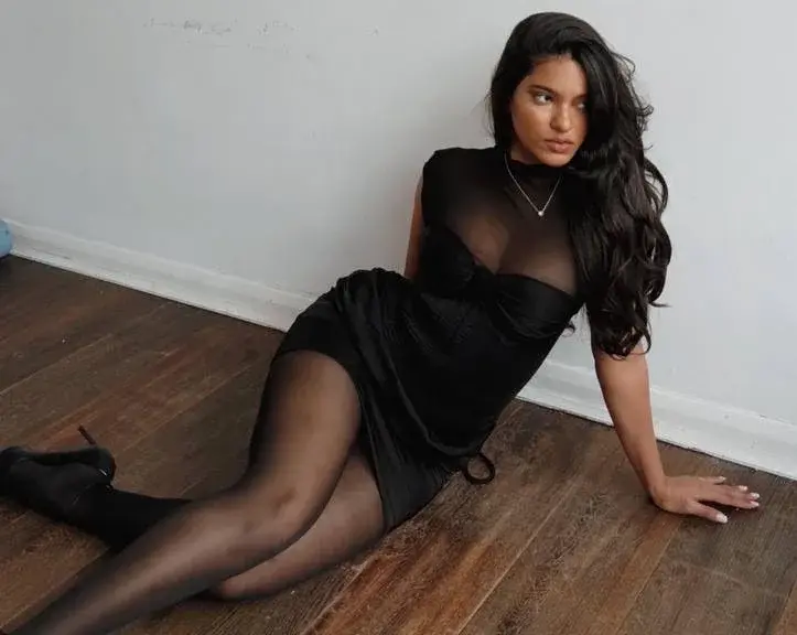 Woman in black dress and tights sitting on wooden floor
