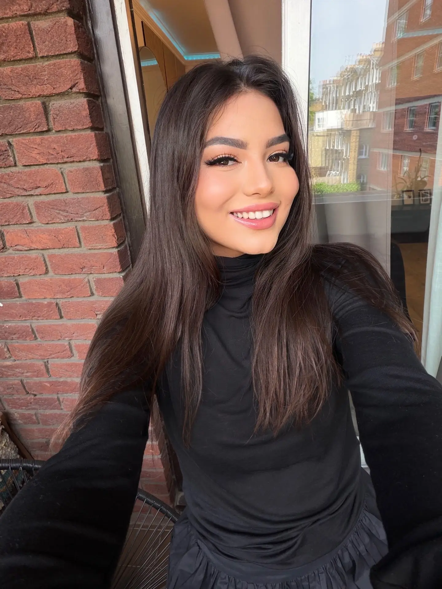 Smiling woman with long dark hair wearing black turtleneck.