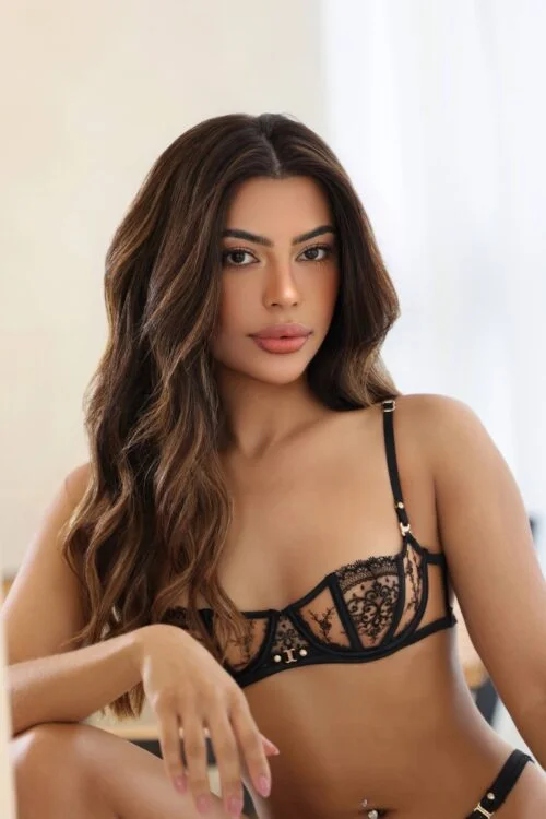 A woman with long wavy hair wearing black lace lingerie.