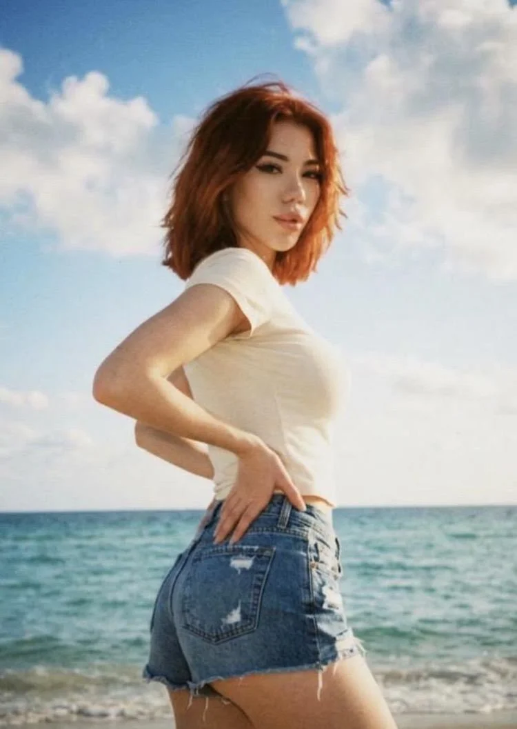 Woman with red hair posing on a sunny beach.