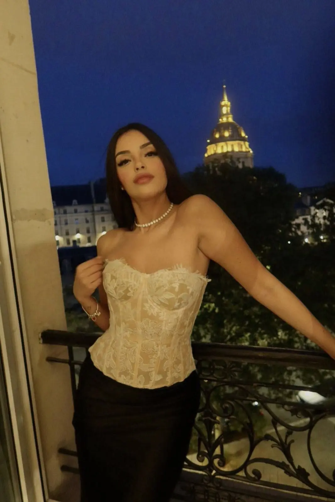 Woman in a cream corset on a Paris balcony.