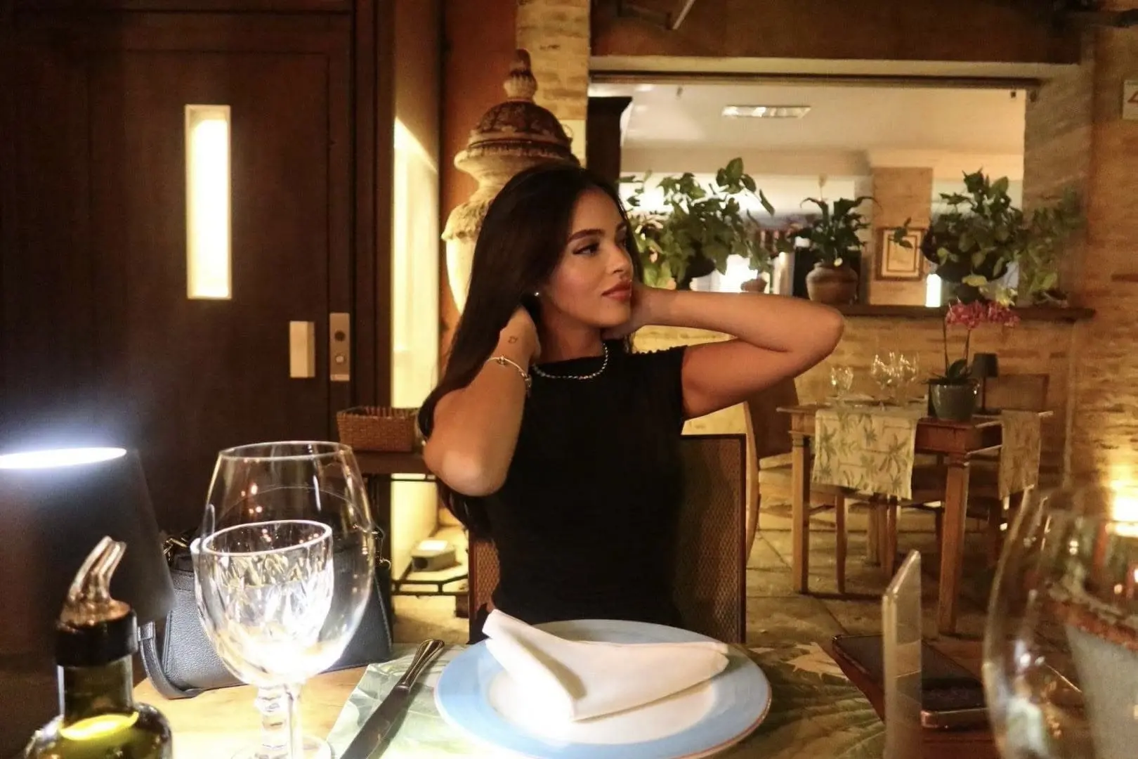 Woman in black top dining at an elegant restaurant.