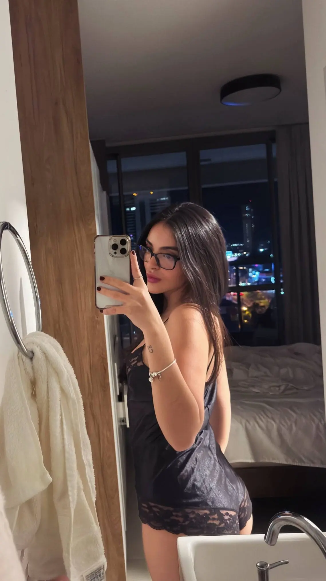 Woman in black lace nightwear taking a mirror selfie.