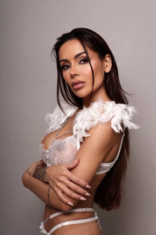 Woman in white lace lingerie with feather shoulder details.