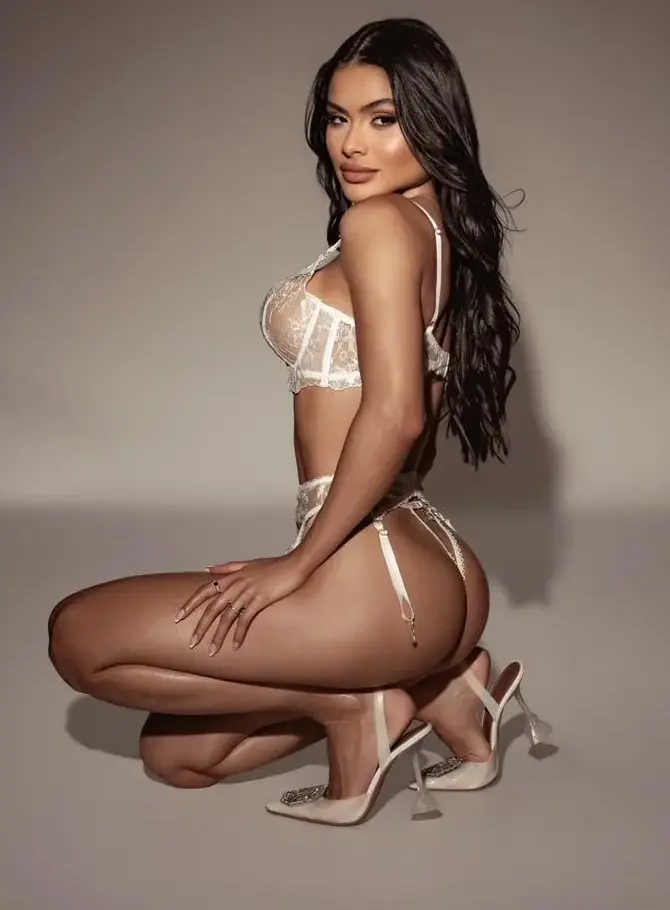 Woman kneeling in white lace lingerie and high heels.