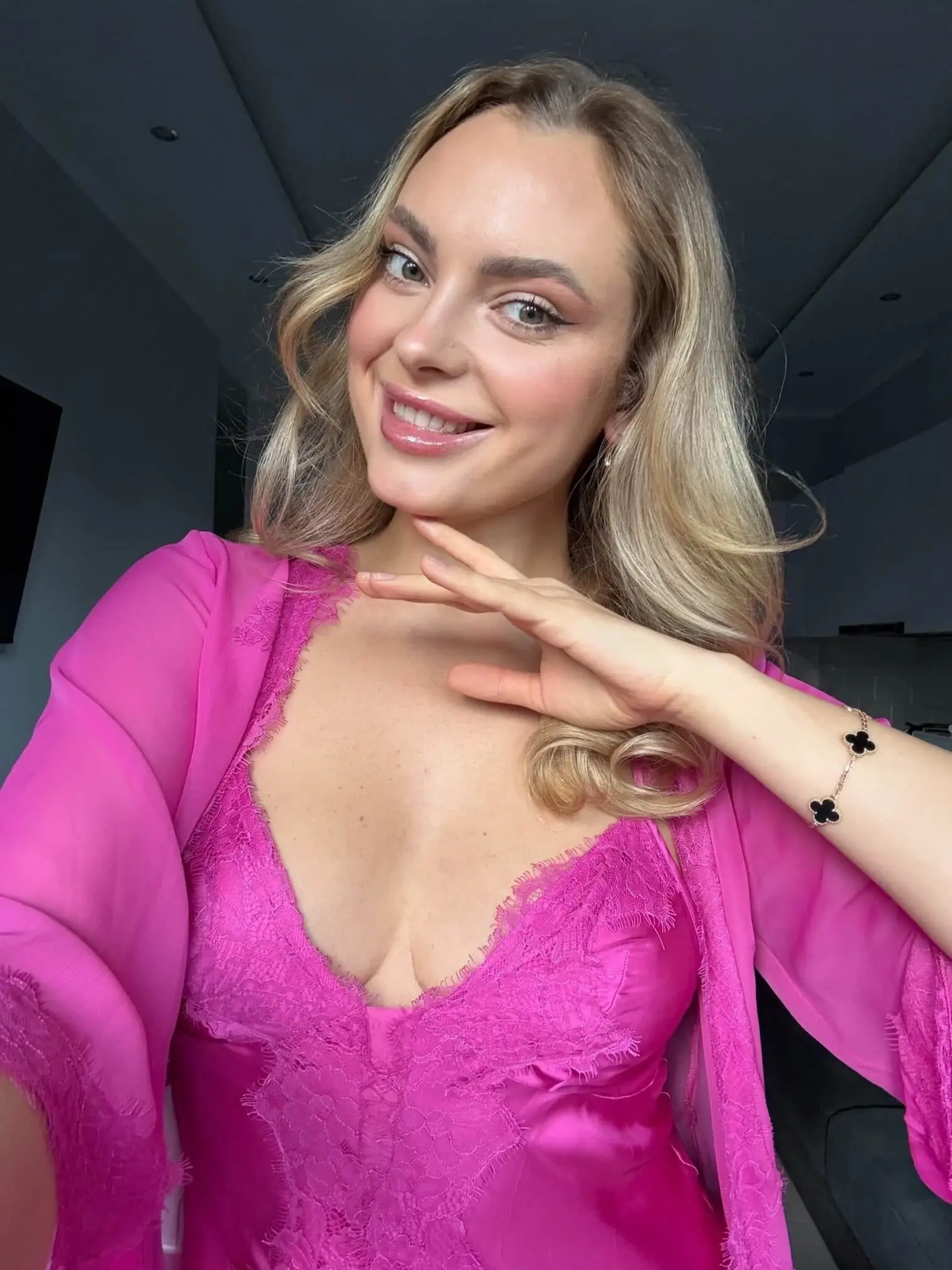 Woman in pink lace lingerie smiling at camera.