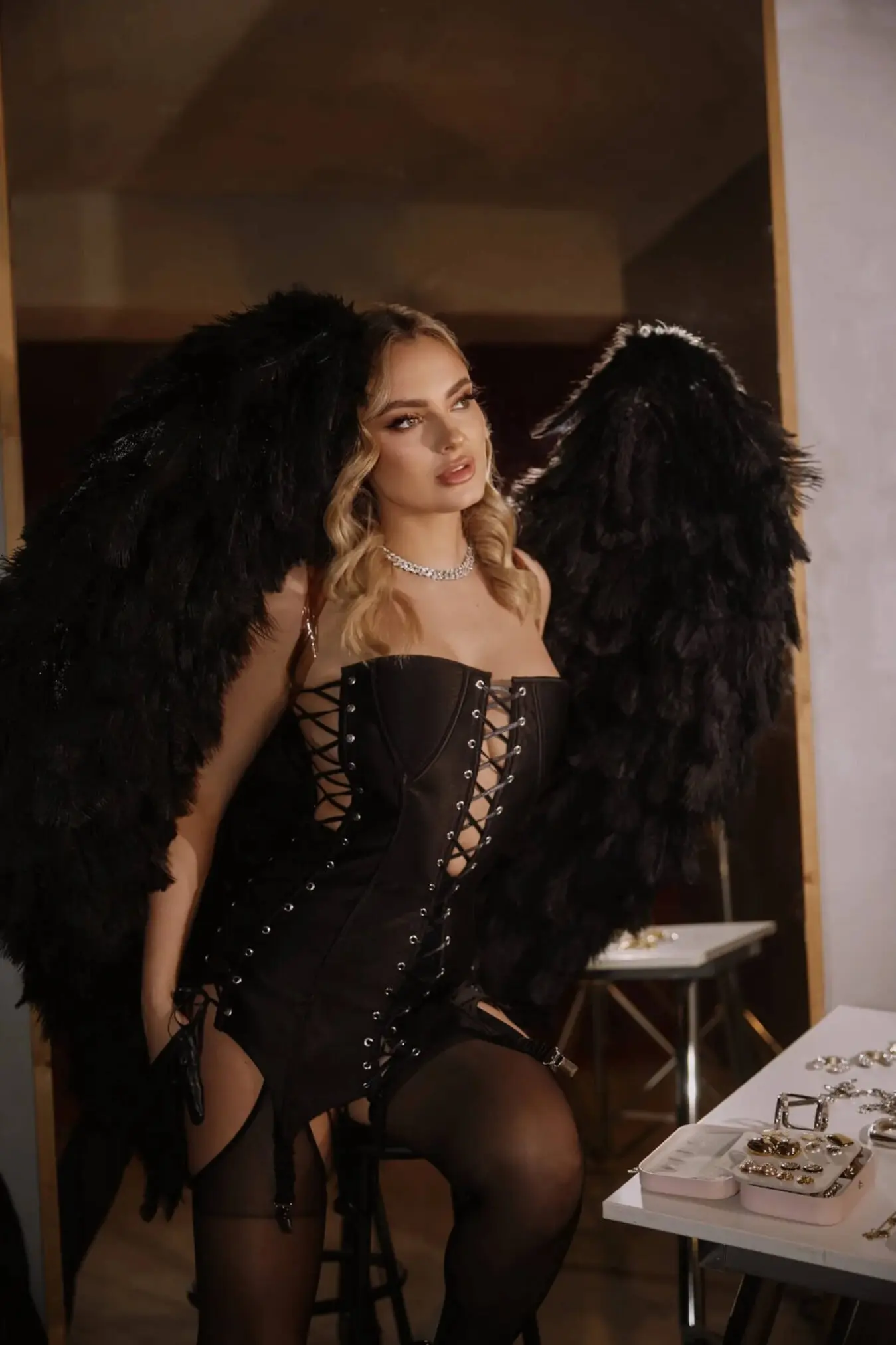 A model wearing a black corset and large black wings.