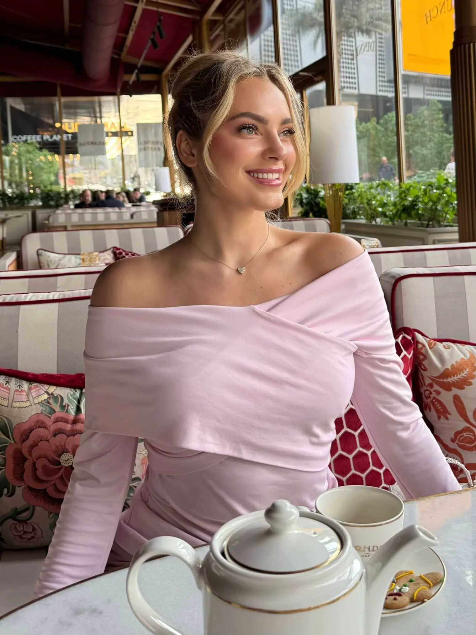 Woman in pink off-the-shoulder top at a cafe.