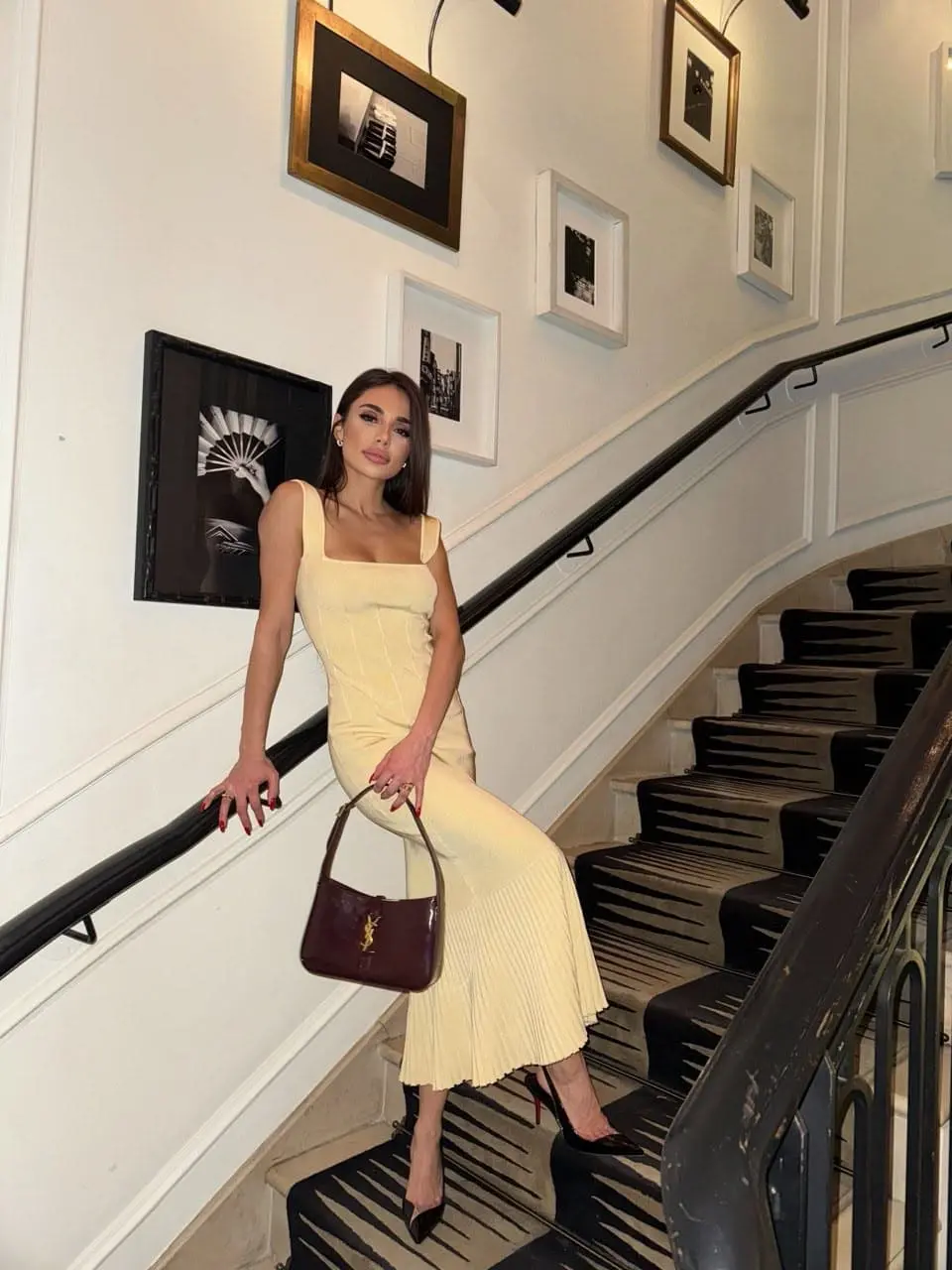 Woman in yellow dress posing on a gallery-style staircase.