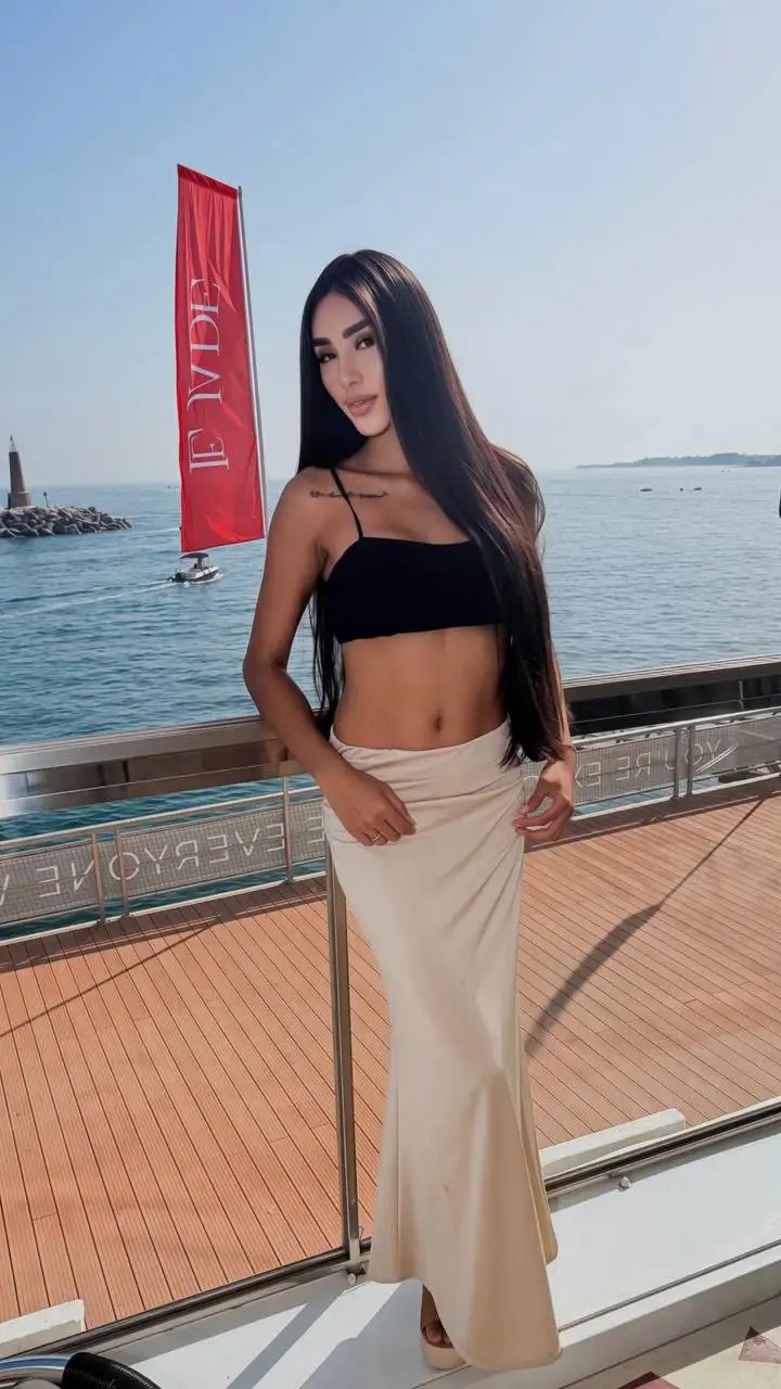 Woman in a black crop top and long cream skirt