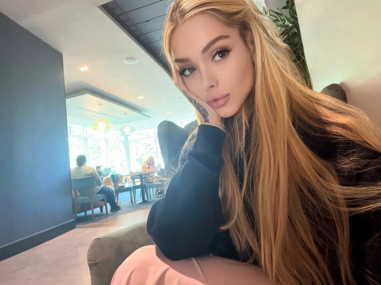 Woman with long blonde hair posing in a cafe
