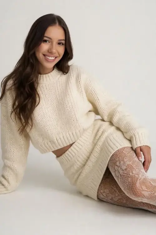 Woman in a cream knitted co-ord set and lace tights.