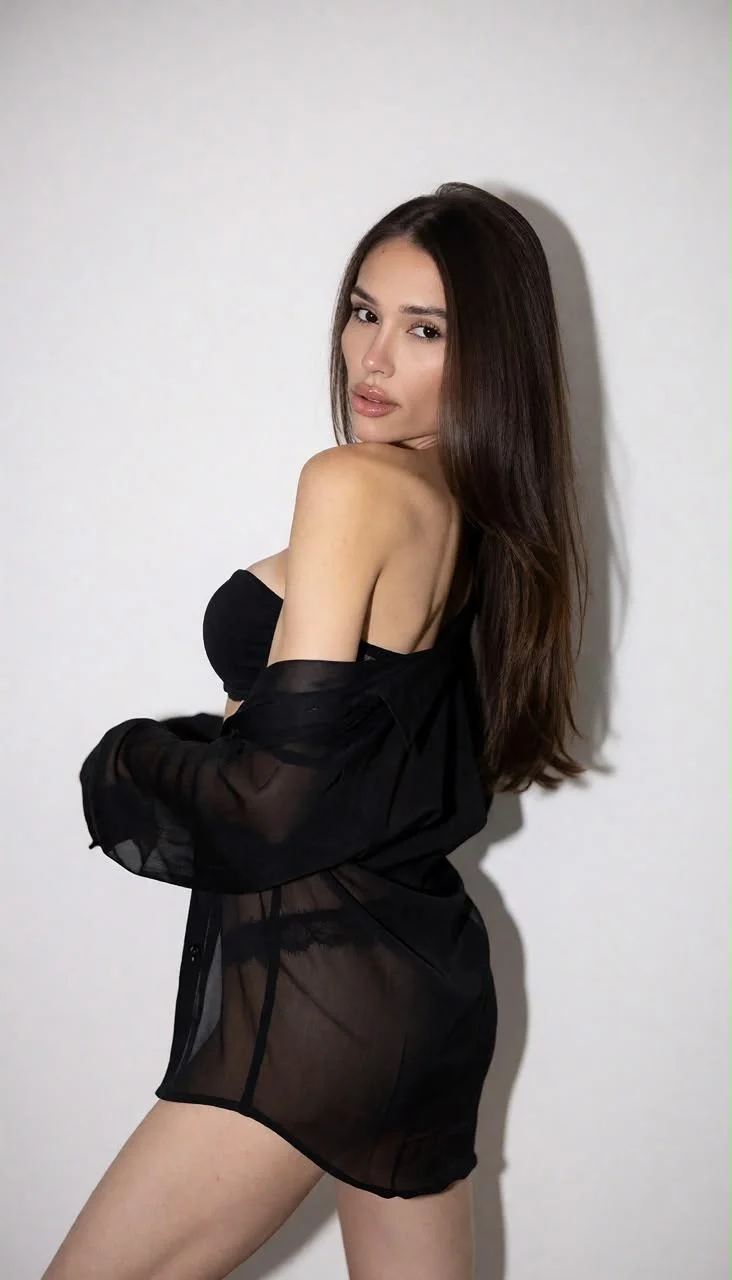 Woman in black lingerie and sheer shirt posing.