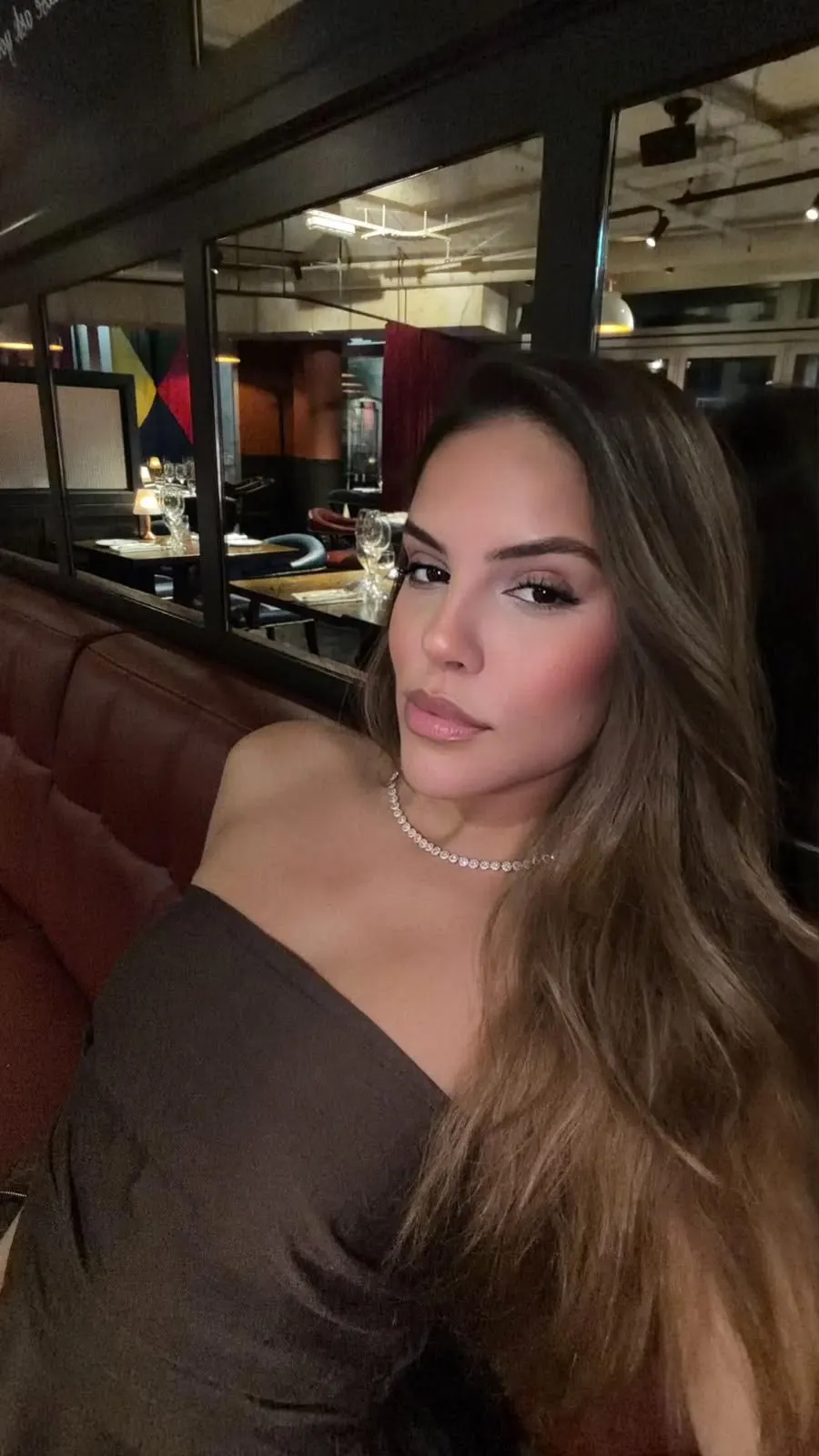 Woman wearing strapless top and necklace in a restaurant.