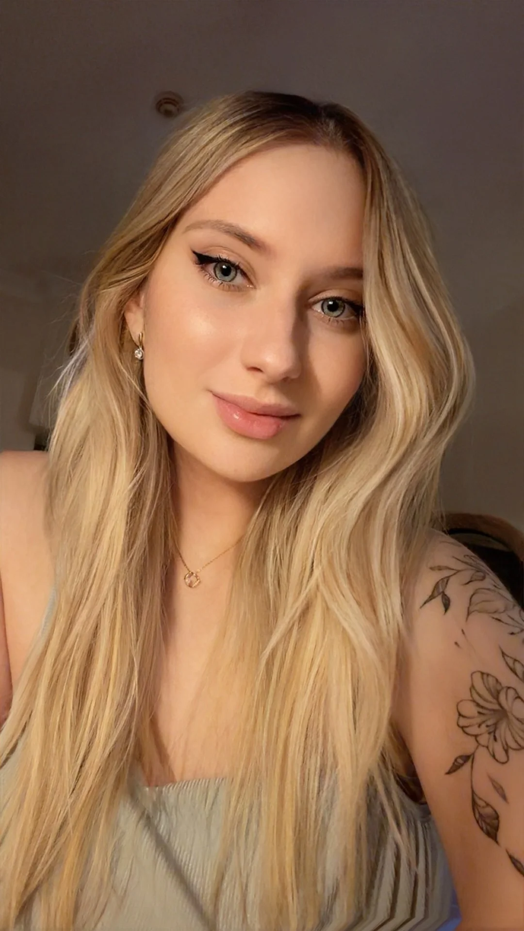 Close-up portrait of a blonde woman with a shoulder tattoo.
