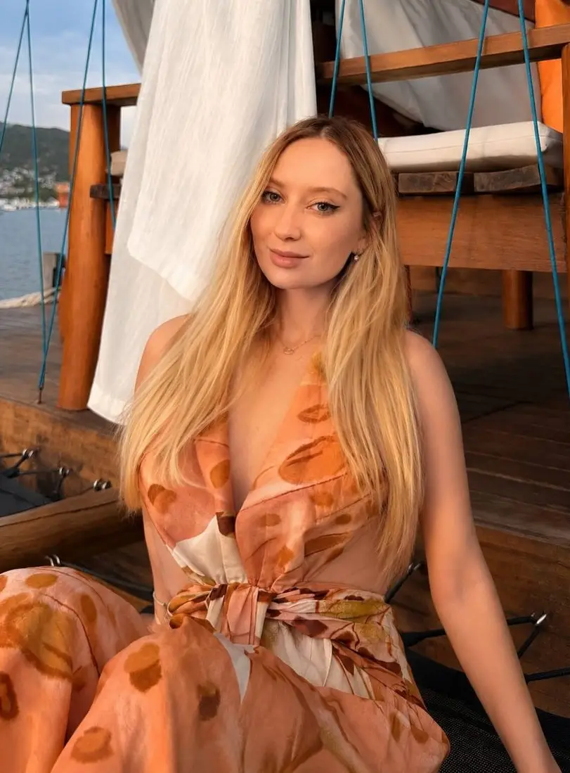 Blonde woman in orange patterned dress on wooden boat deck