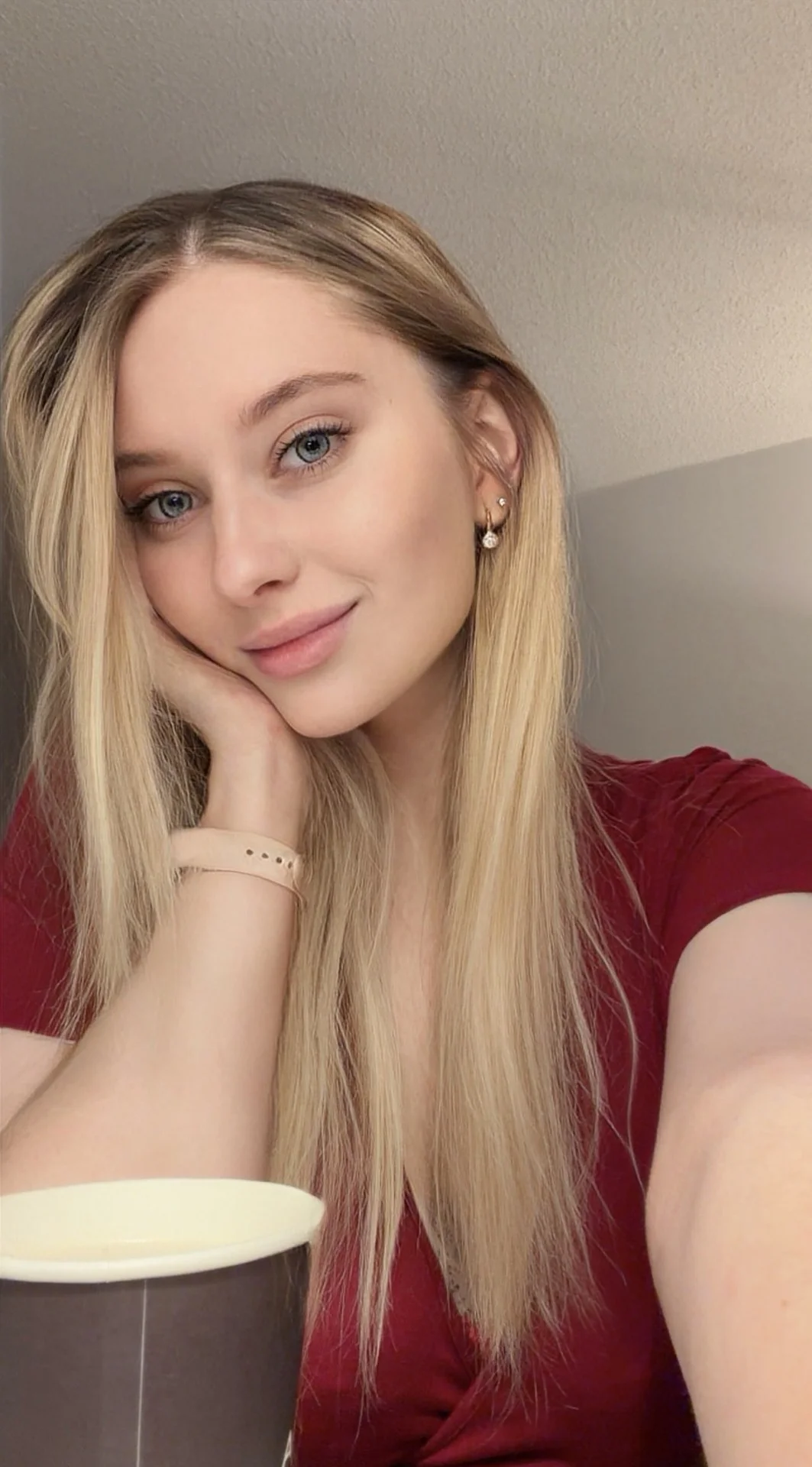 Young woman with long blonde hair leaning on her hand.