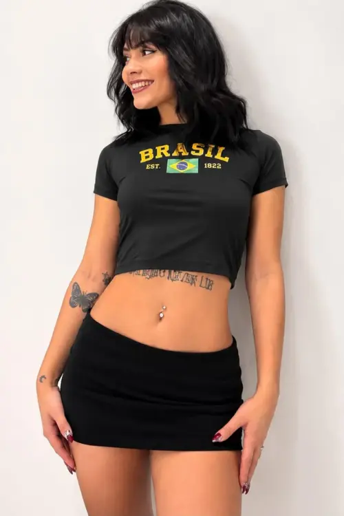 Woman wearing a black Brasil crop top and mini skirt.