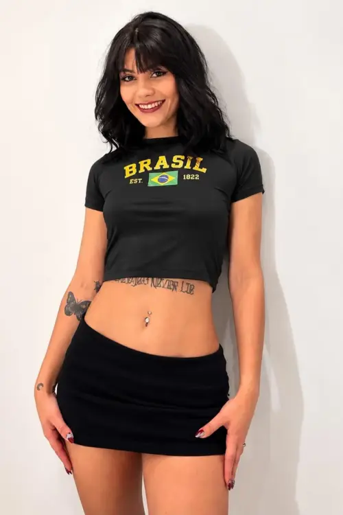 Smiling woman wearing a black Brazil crop top and skirt.
