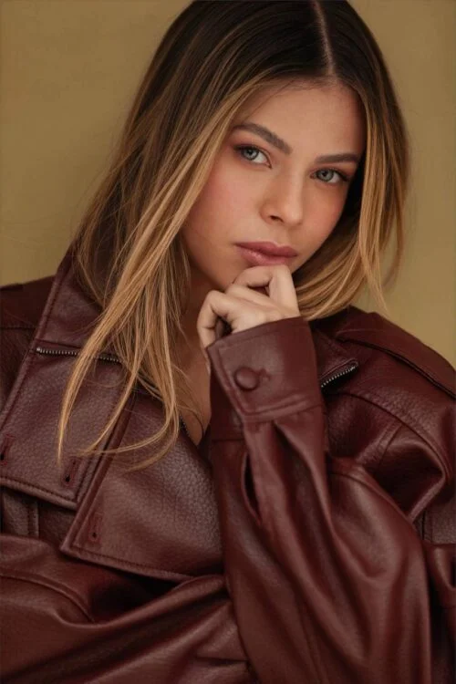 A woman with long hair in a burgundy leather jacket