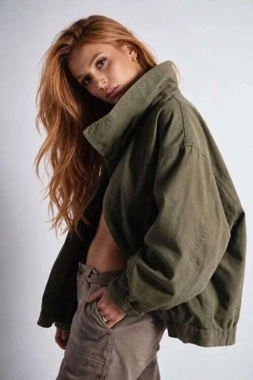 Redheaded woman posing in an oversized green jacket.