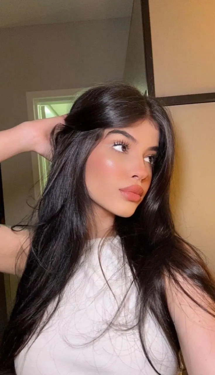 A young woman with long dark hair looking away.